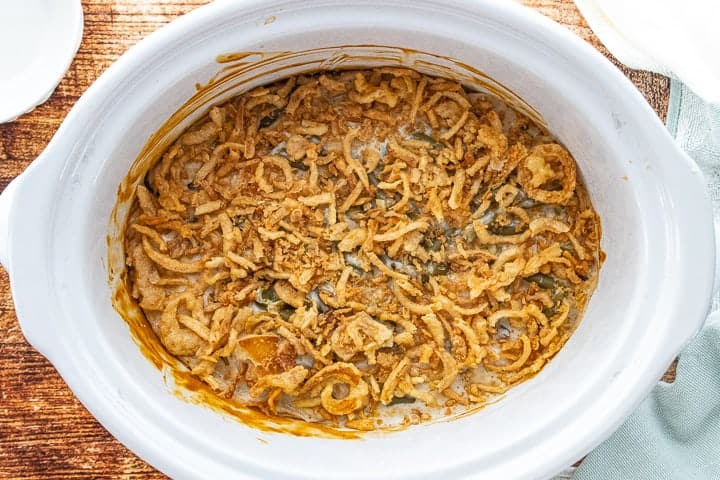 Crockpot Green Bean Casserole, a green bean casserole for a crowd, showing cooked casserole with French fried onions on the top. 