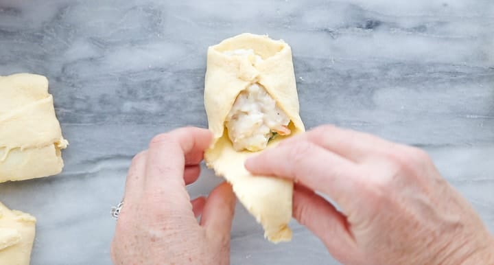 Chicken Pot Pie with Crescent Rolls, a crescent roll chicken pot pie recipe, showing pot pie filling being rolled into a crescent roll.