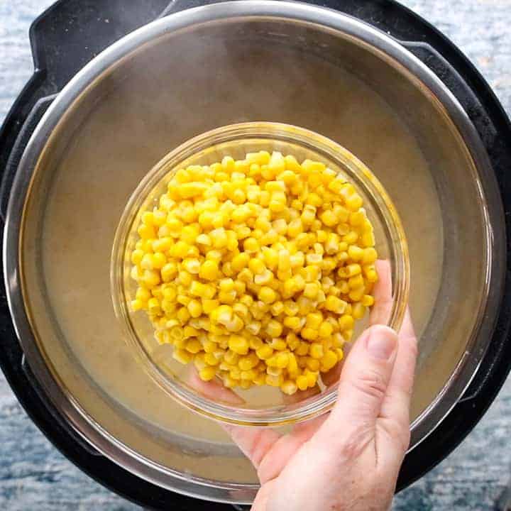 A person holding a bowl of corn over instant pot