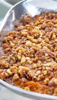 a stainless steel bowl with sweet potato crunch with a brown sugar and pecan topping.