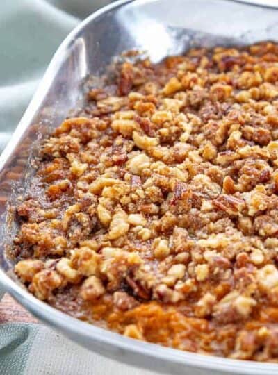 a stainless steel bowl with sweet potato crunch with a brown sugar and pecan topping.