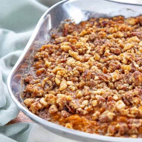 a stainless steel bowl with sweet potato crunch with a brown sugar and pecan topping.