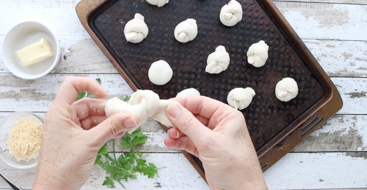 dinner roll dough being tied into a knot