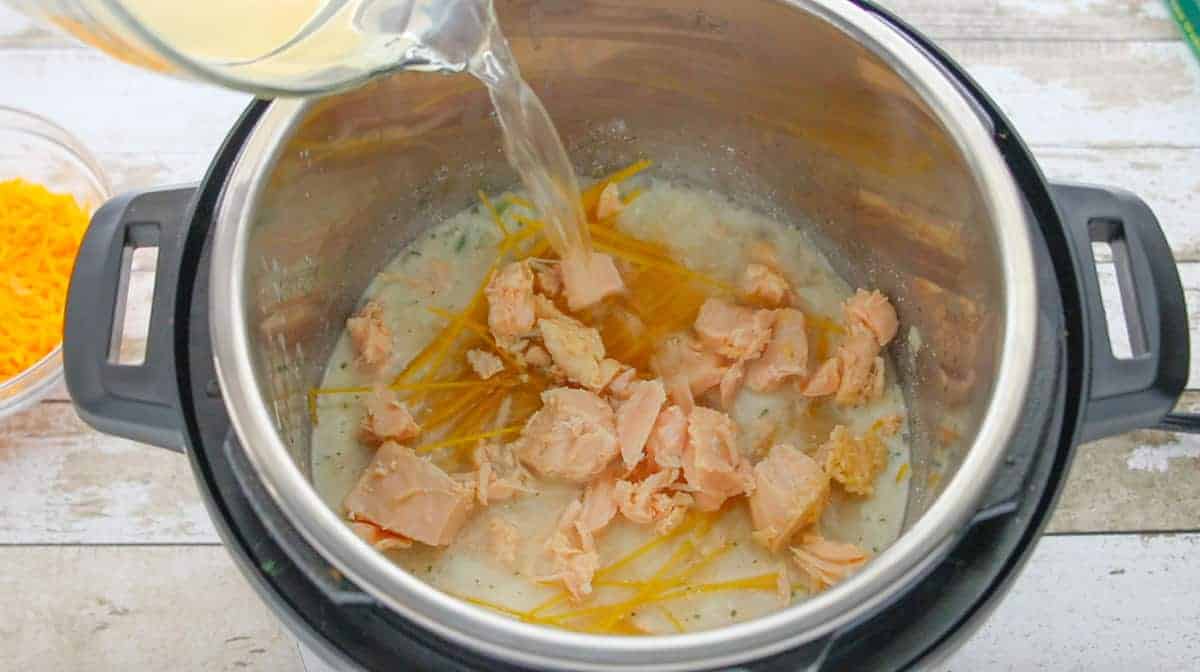chicken broth being added to the instant pot filled with chicken spaghetti ingredients.