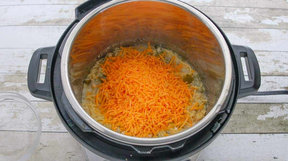  shredded cheese being added to the instant pot.
