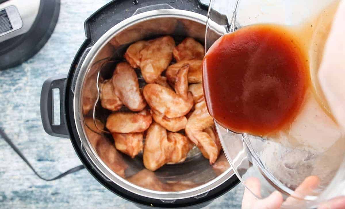 sauce being added to raw chicken in instant pot