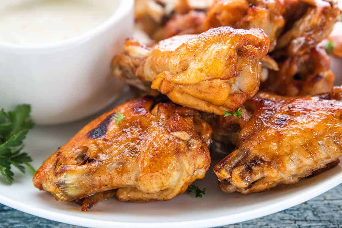 chicken wings on a plate with dipping sauce on the side of the plate.