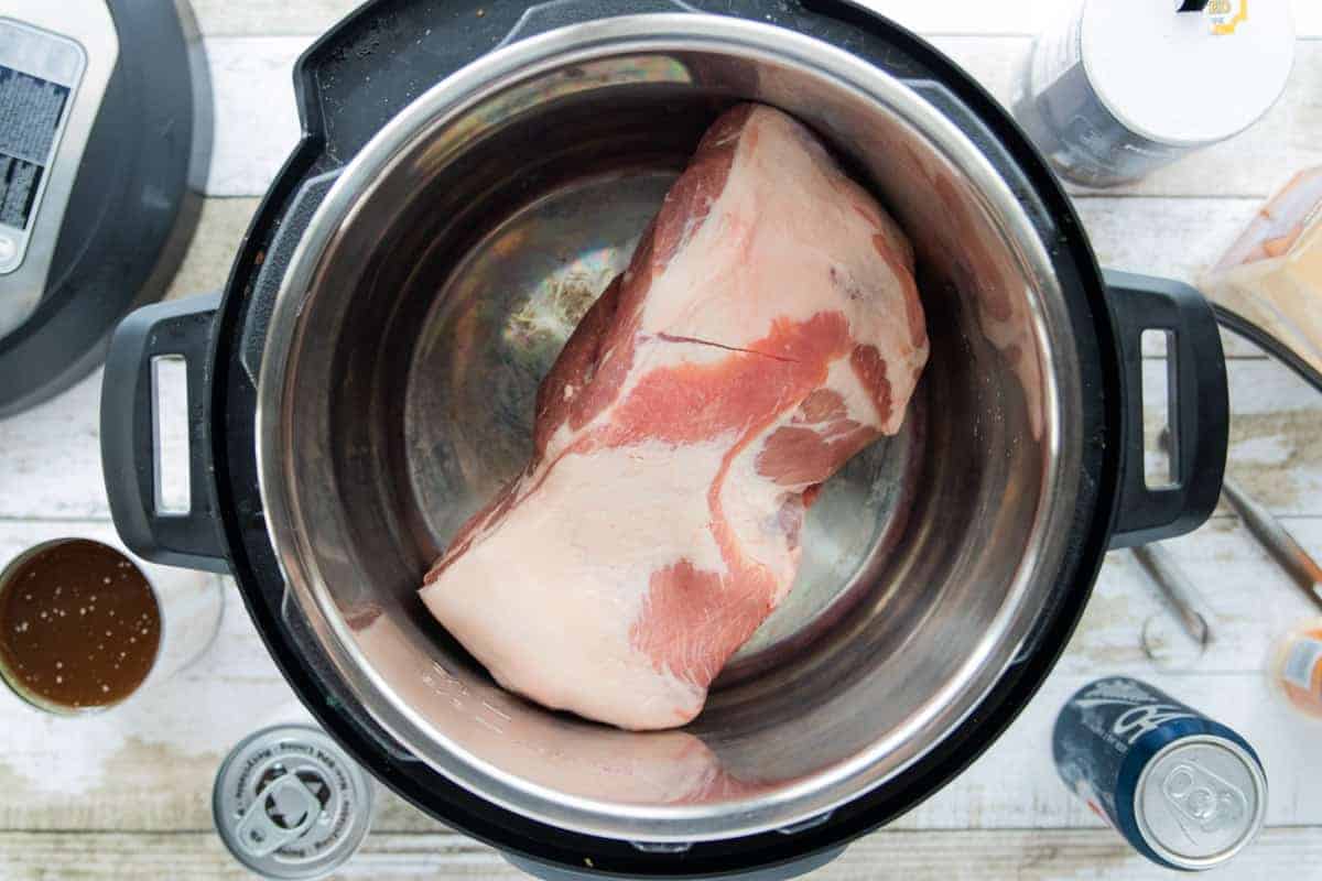 a rump roast in an Instant pot with ingredients surrounding the instant pot all on top of a wooden countertop.