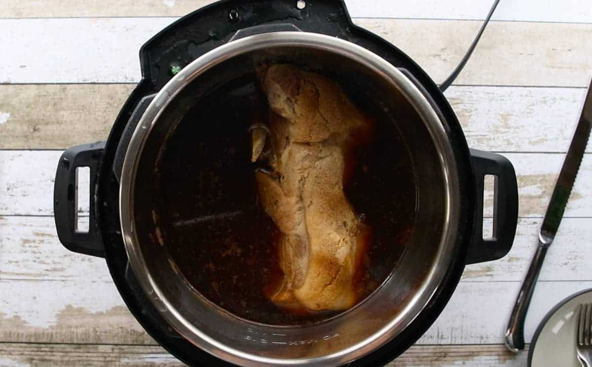 a cooked rump roast in an instant pot sitting on top of a wooden countertop.