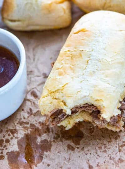 A close up of a sandwich and a bowl of French dip sauce