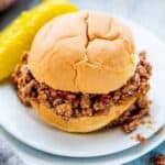 A turkey sloppy Joe on a bun with ketchup with the sloppy Joe spilling out of the bun on a white plate.