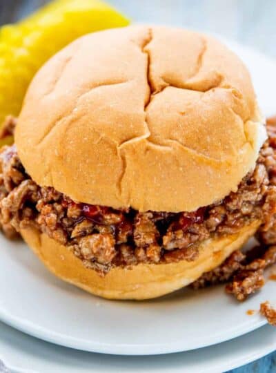 A turkey sloppy Joe on a bun with ketchup with the sloppy Joe spilling out of the bun on a white plate.