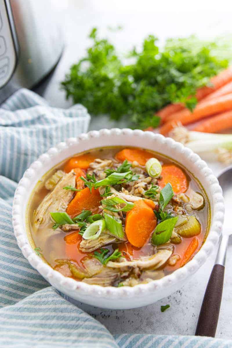 Instant Pot Chicken & Rice Soup showing soup in a white bowl on a granite countertop.