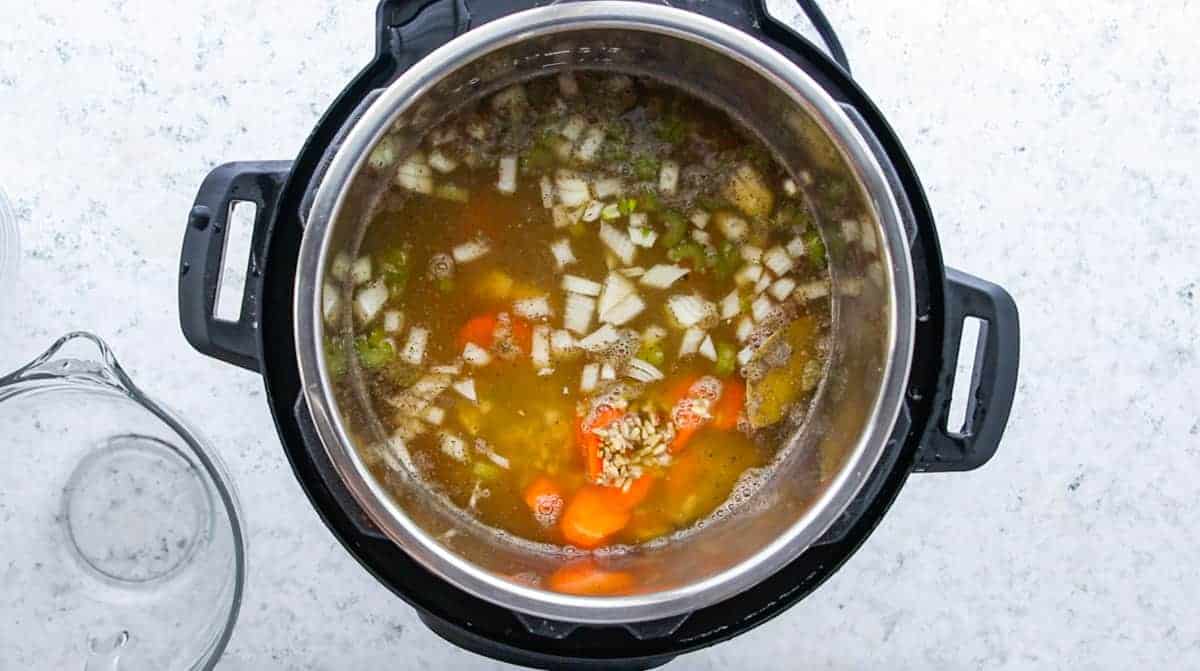 Instant Pot Chicken & Rice Soup showing an instant pot filled with soup on a granite countertop.