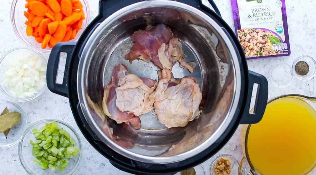 Chicken Stew recipe showing all the ingredients like carrots, onions, bay leaves, rice, celery, chicken and chicken stock.