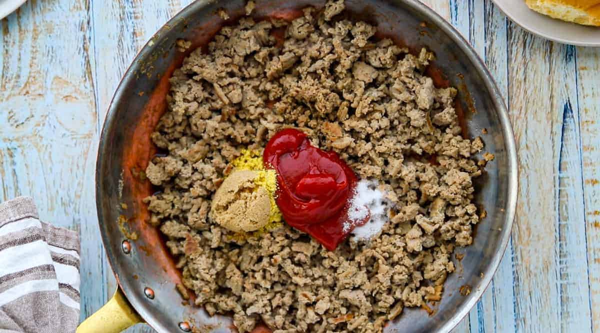  browned ground turkey in the skillet with sauce ingredients added to the skillet.