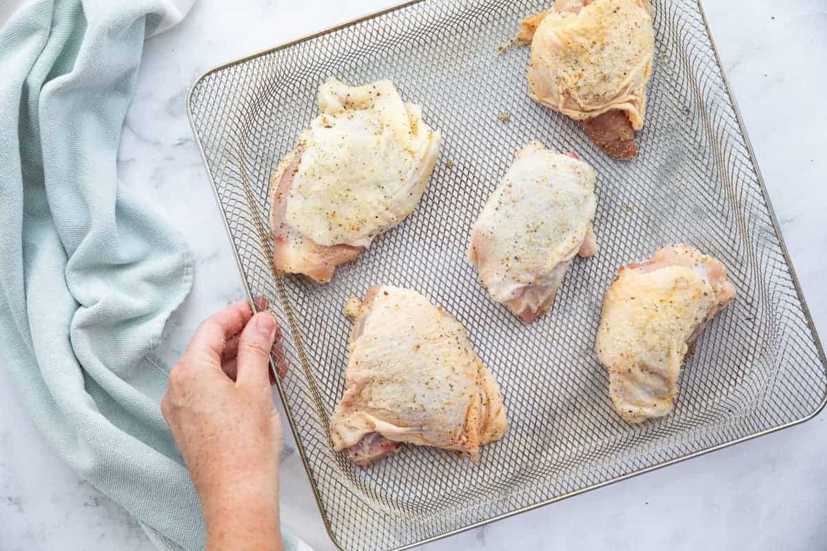 Raw chicken thighs on an air fryer rack.