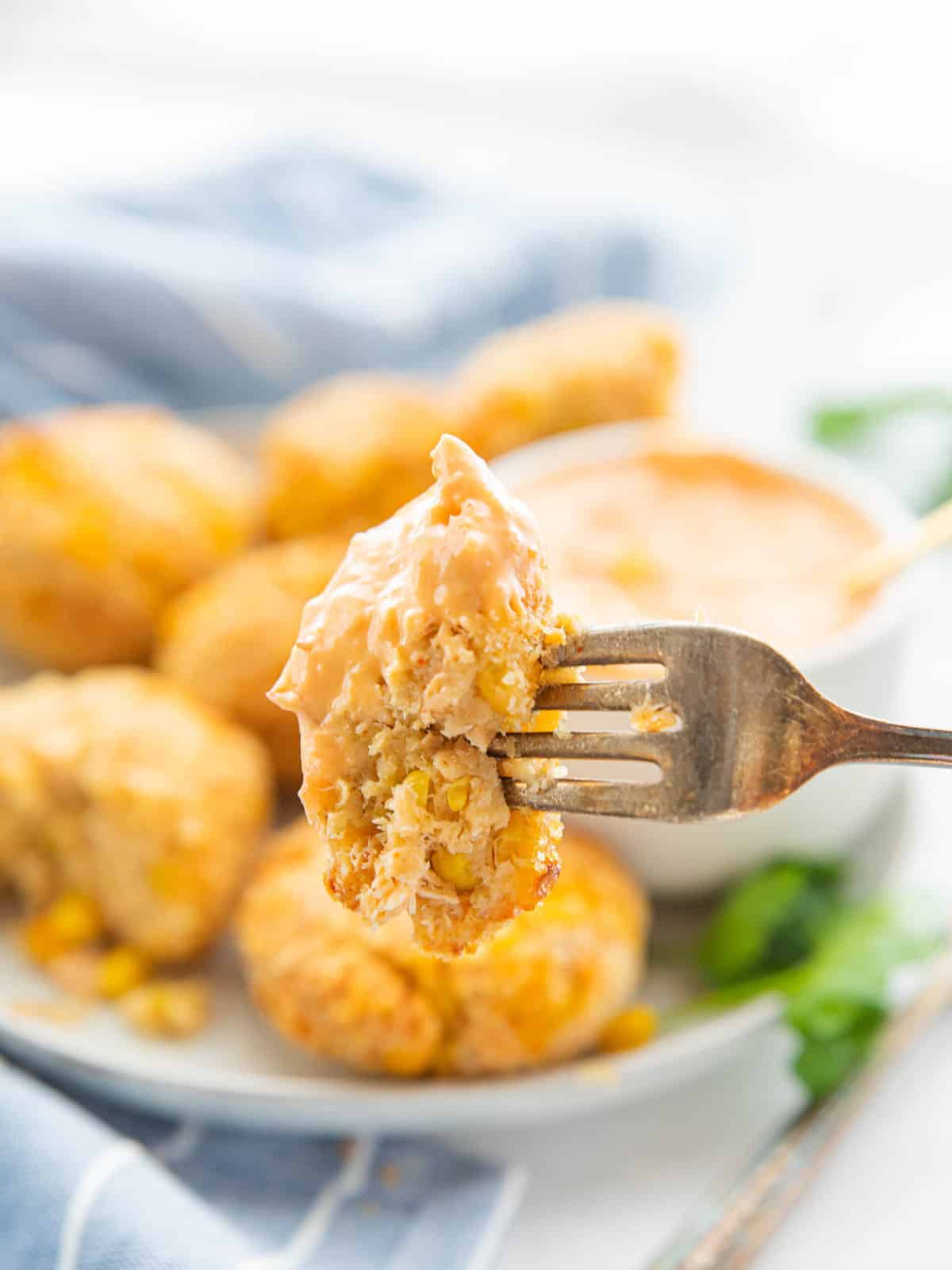 Air Fryer Salmon Patties showing the salmon patties on a serving platter with one being dipped in sauce all on top of a countertop.