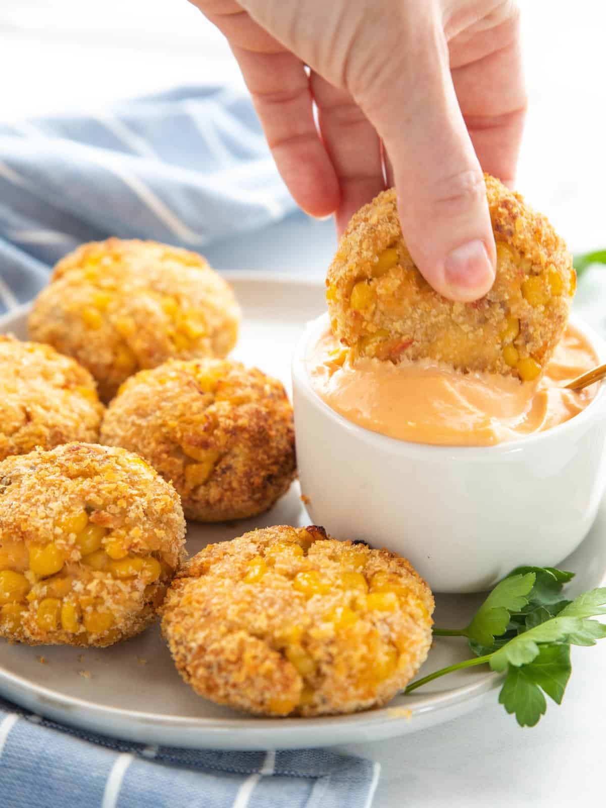 Air Fryer Salmon Patties showing the salmon patties on a serving platter with one being dipped in sauce all on top of a countertop.