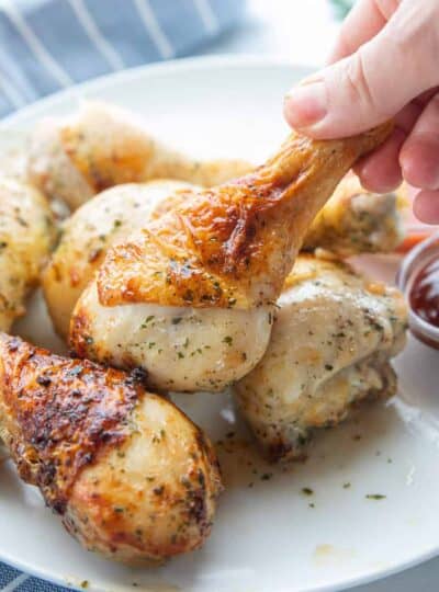 chicken legs on a plate with on being picked up