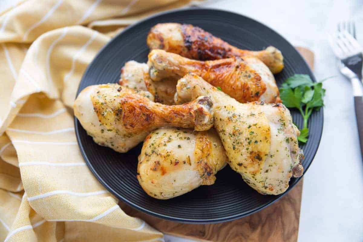 Air Fryer Drumsticks showing chicken wings on a serving patter with a towel on the side all on top of a countertop.