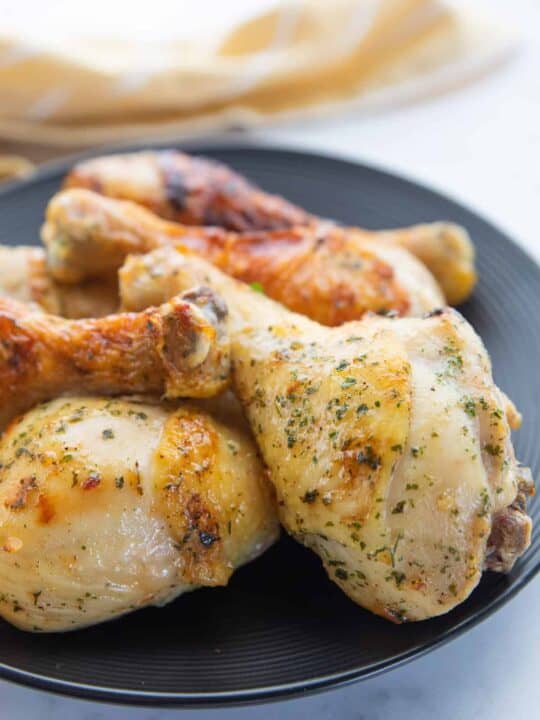 Air Fryer Drumsticks showing chicken wings on a serving patter with a towel on the side all on top of a countertop.