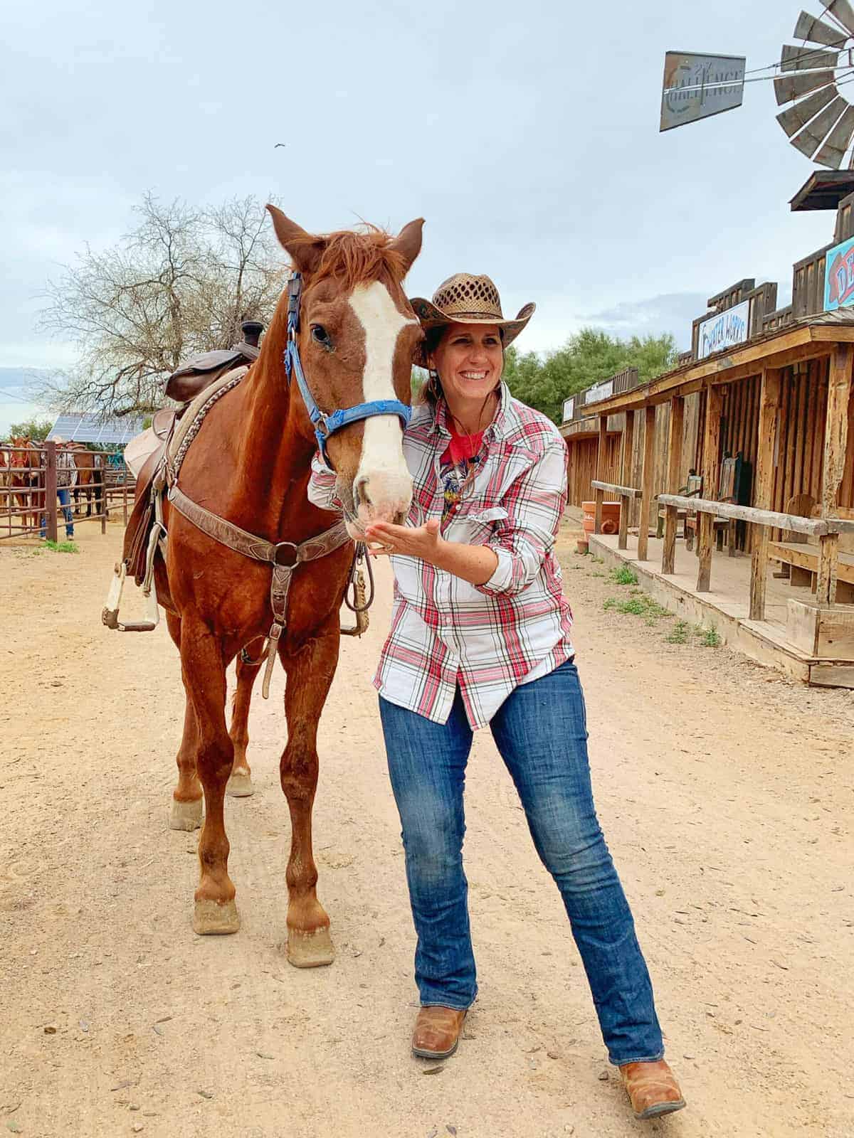 White Stallion Ranch, the Best All-Inclusive Resort in Arizona showing a women standing next to a horse. named Saguaro on the dude ranch.