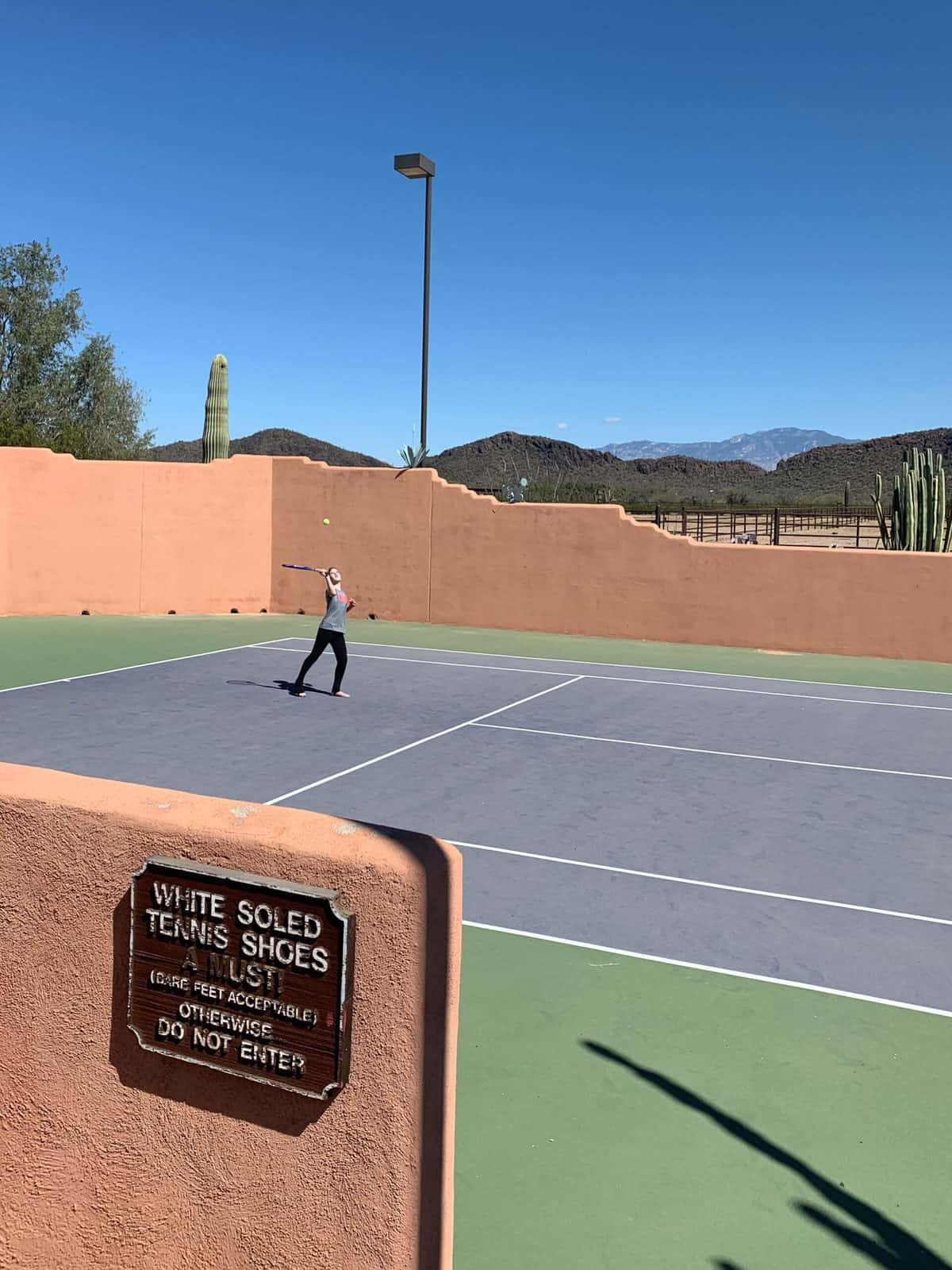 White Stallion Ranch, the Best All-Inclusive Resort in Arizona showing the tennis court at the dude ranch with a young kid playing a game of tennis.