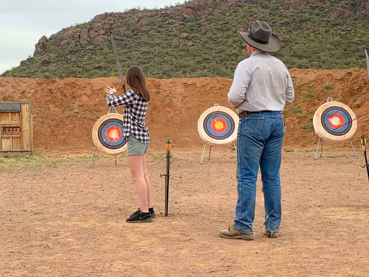 White Stallion Ranch, the Best All-Inclusive Resort in Arizona showing a professional overseeing a young girl practicing archery.