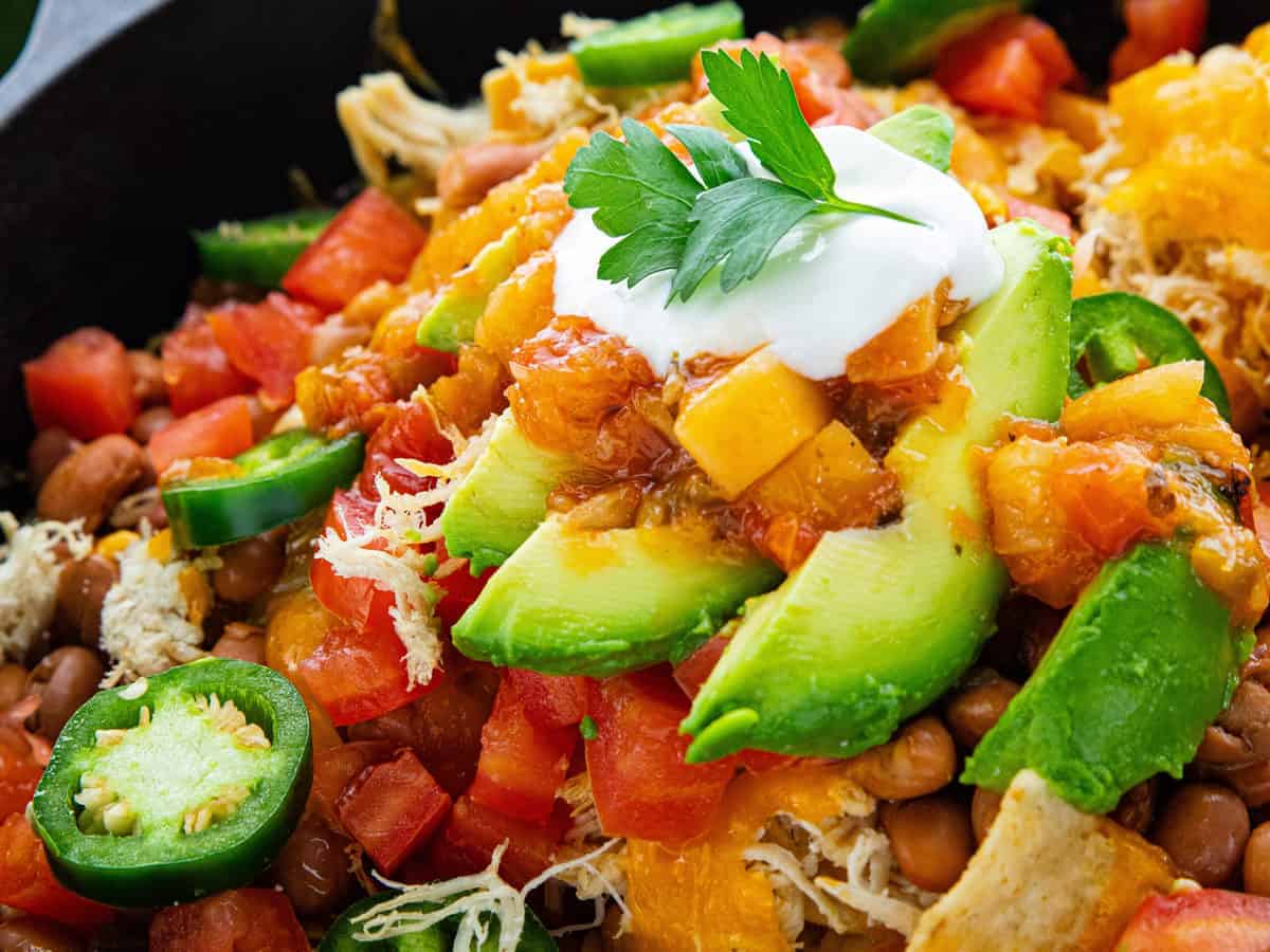 Shredded Chicken Skillet Nachos showing nachos in a cast iron skillet.