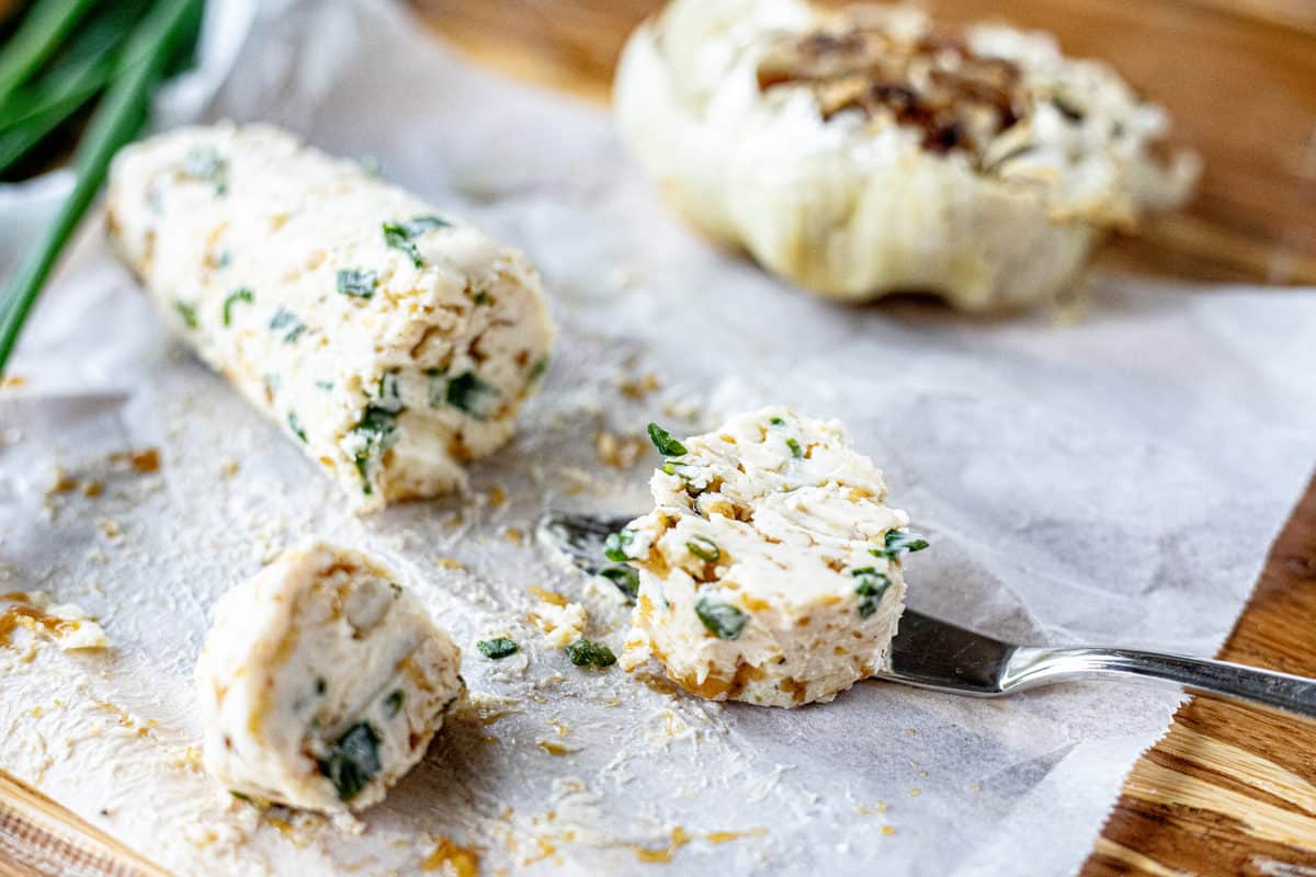 Compound butter shown on wax paper with scallions and roasted garlic sliced.