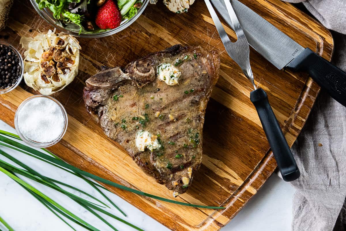 A knife sitting on top of a wooden cutting board, with Steak