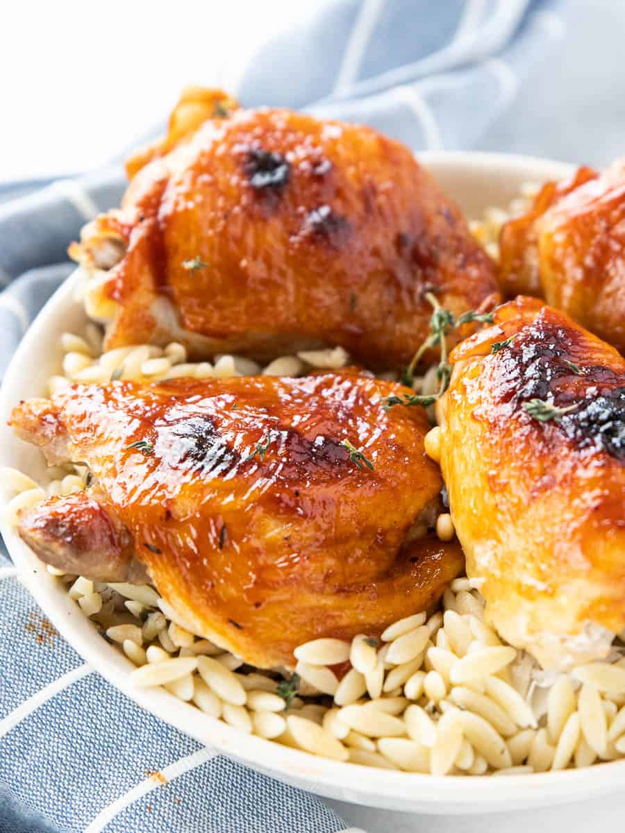 Poached chicken thighs in a serving bowl with cooked rice. 