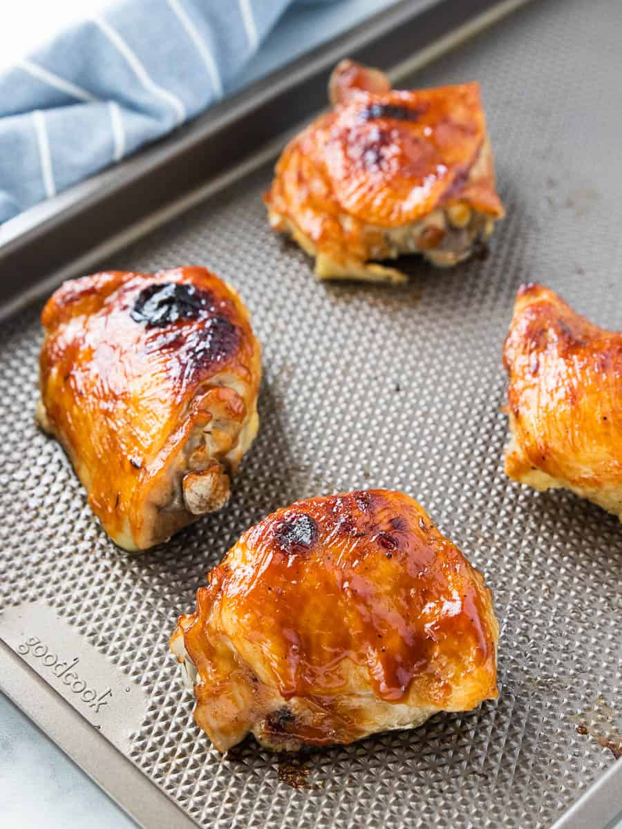 Boiled chicken thighs on a baking sheet basted with BBQ sauce and broiled. 