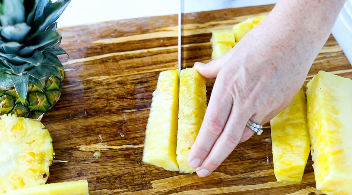 A fresh pineapple section is being cut in half.