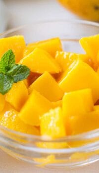 A close up of a bowl of cubed mango in a clear glass dish.