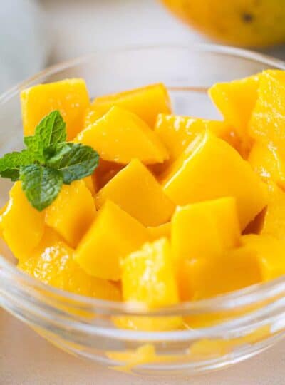 A close up of a bowl of cubed mango in a clear glass dish.