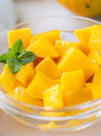 A close up of a bowl of cubed mango in a clear glass dish.