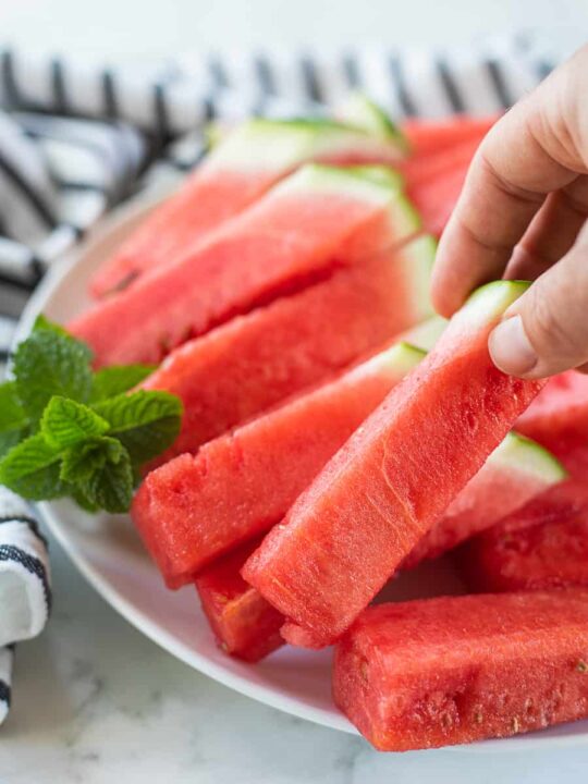 a hand holding up a watermelon stick