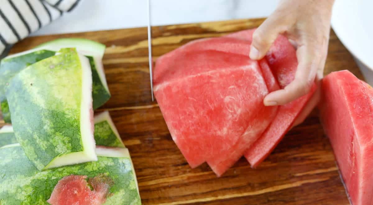 Watermelon slices with no rind getting turned onto its flat side.