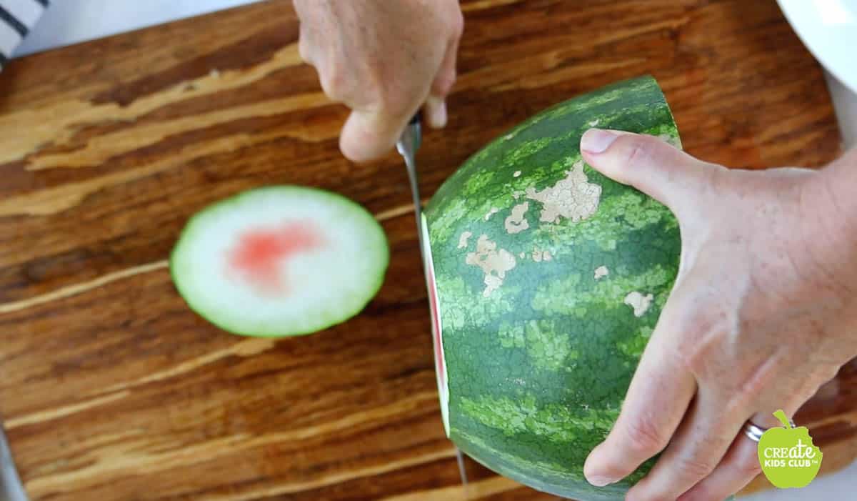 Half of a watermelon with the end getting sliced off. 