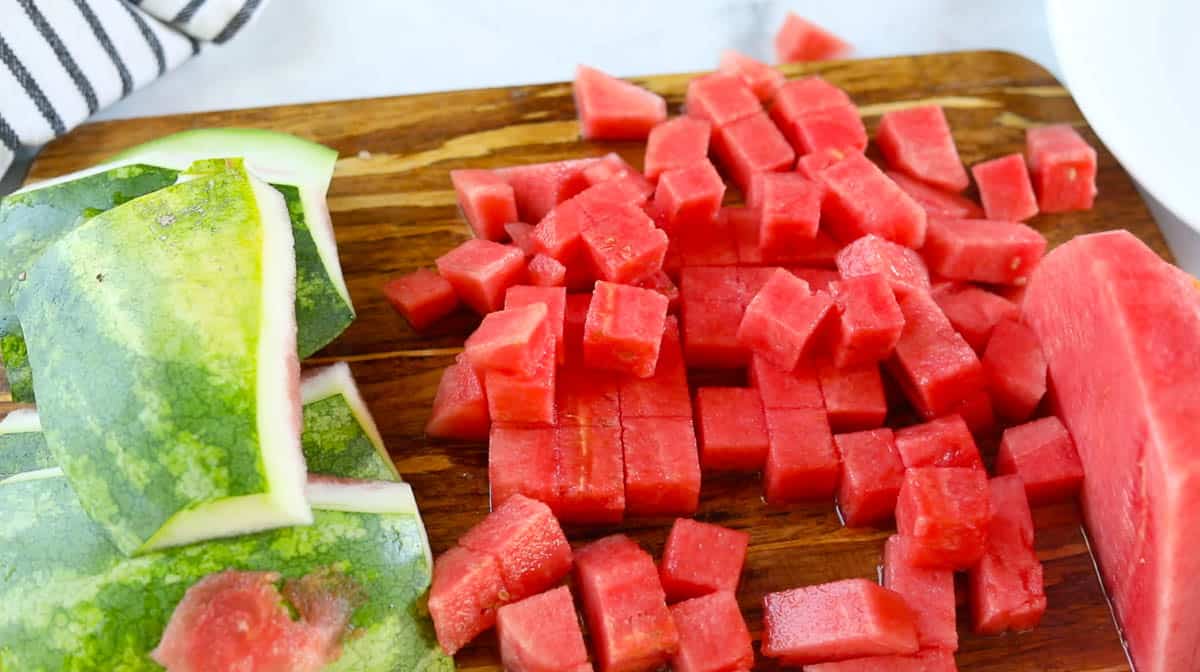 Sliced watermelon cubes on a cutting board next to the rind.