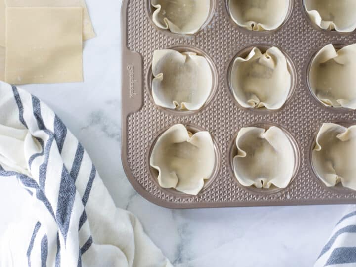 Uncooked wonton wrappers formed into muffin tin to shape them into cups after baking.
