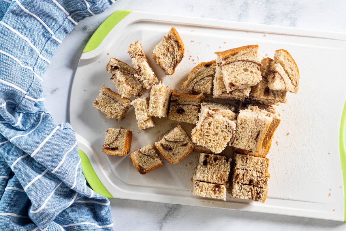 Chopped cubes of bread on a white cutting board.