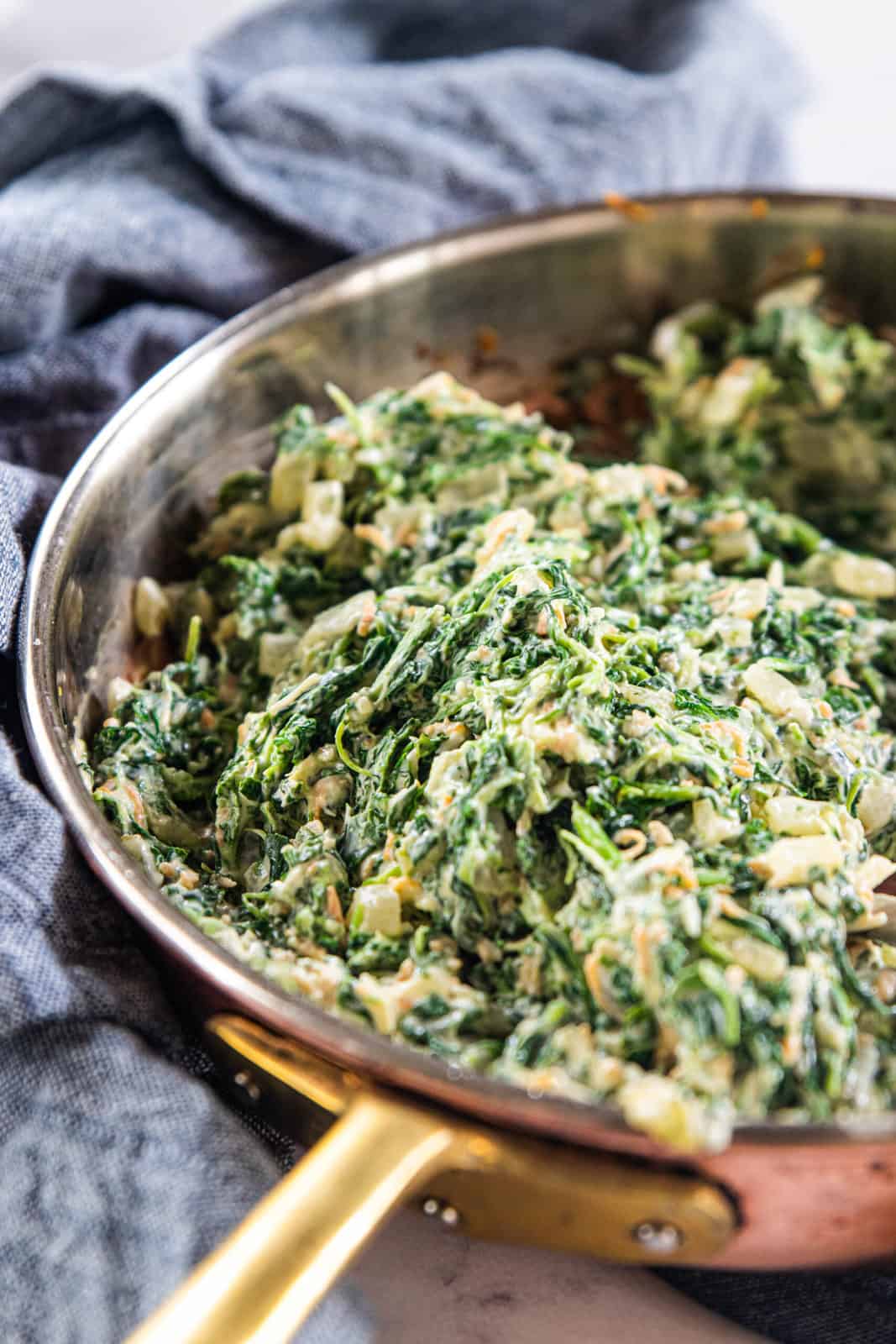 A skillet being shown filled with spinach dip. 