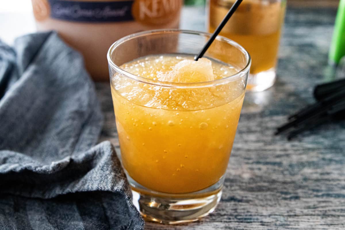 Brandy Slush being shown in a glass with a drink straw on top of a countertop. 