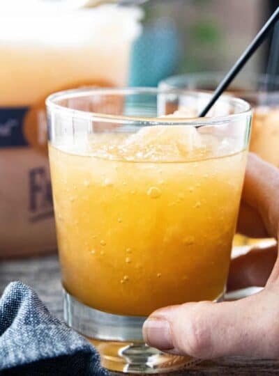 a hand holding a brandy slush in a cocktail glass with a straw