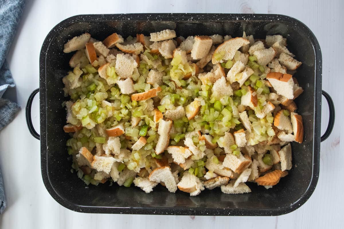 Pieces of torn white bread and diced celery in a large baking pan. 