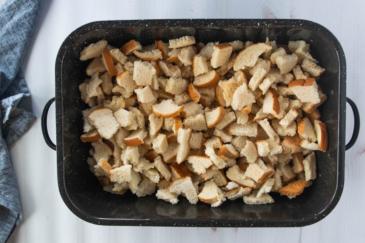 Pieces of torn white bread in a large baking pan.