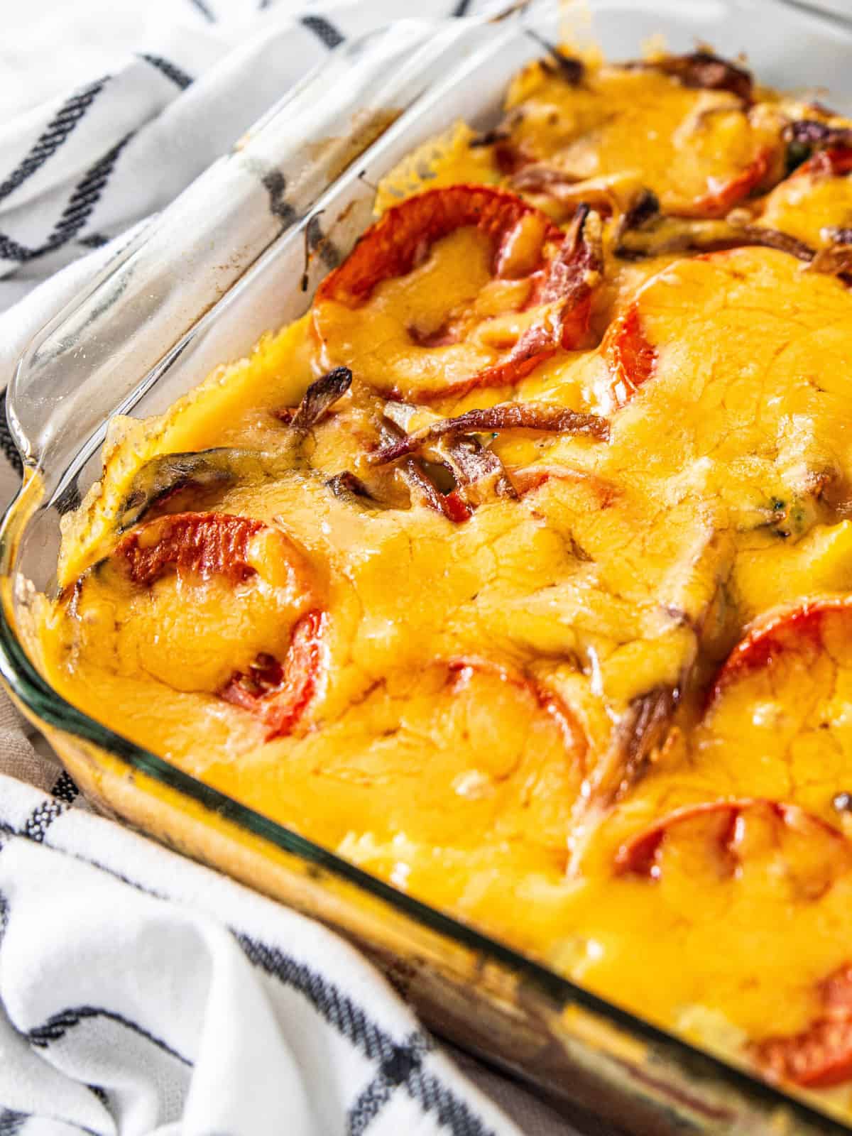 A Vegetable Strata Recipe being shown in a baking dish with melted cheese on the top. 